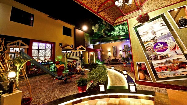 A hotel courtyard with a decorative ceiling, a small slide, and potted plants. - Hotel Royal (Diu)