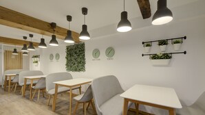 Una sala de reuniones moderna con mesas y sillas de madera, iluminación colgante y relojes de pared que marcan diferentes ciudades.