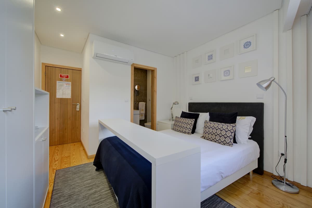 A modern bedroom with a bed, bedside table, and a desk area.