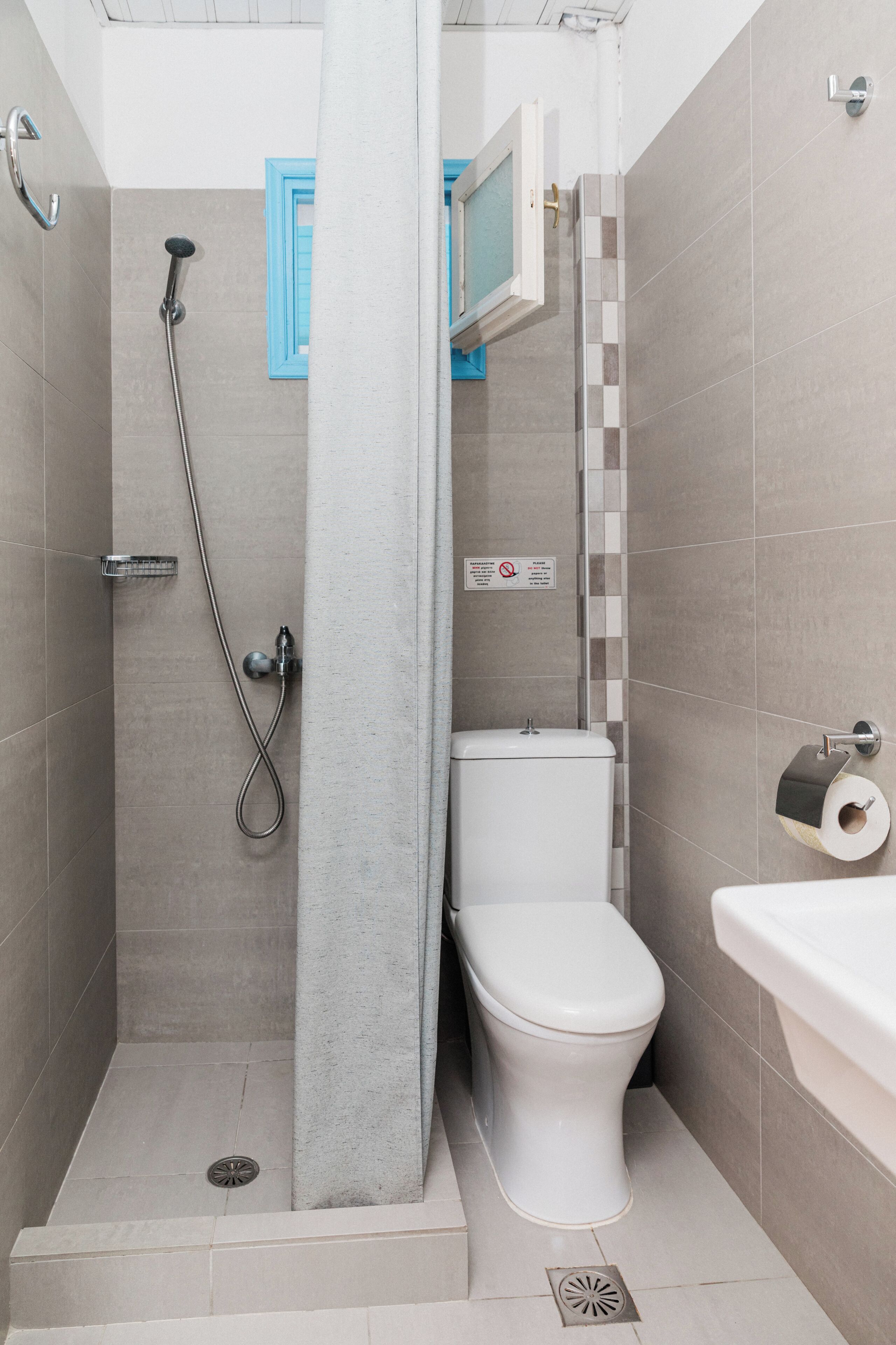 A bathroom with a shower, toilet, sink, and a towel rack.
