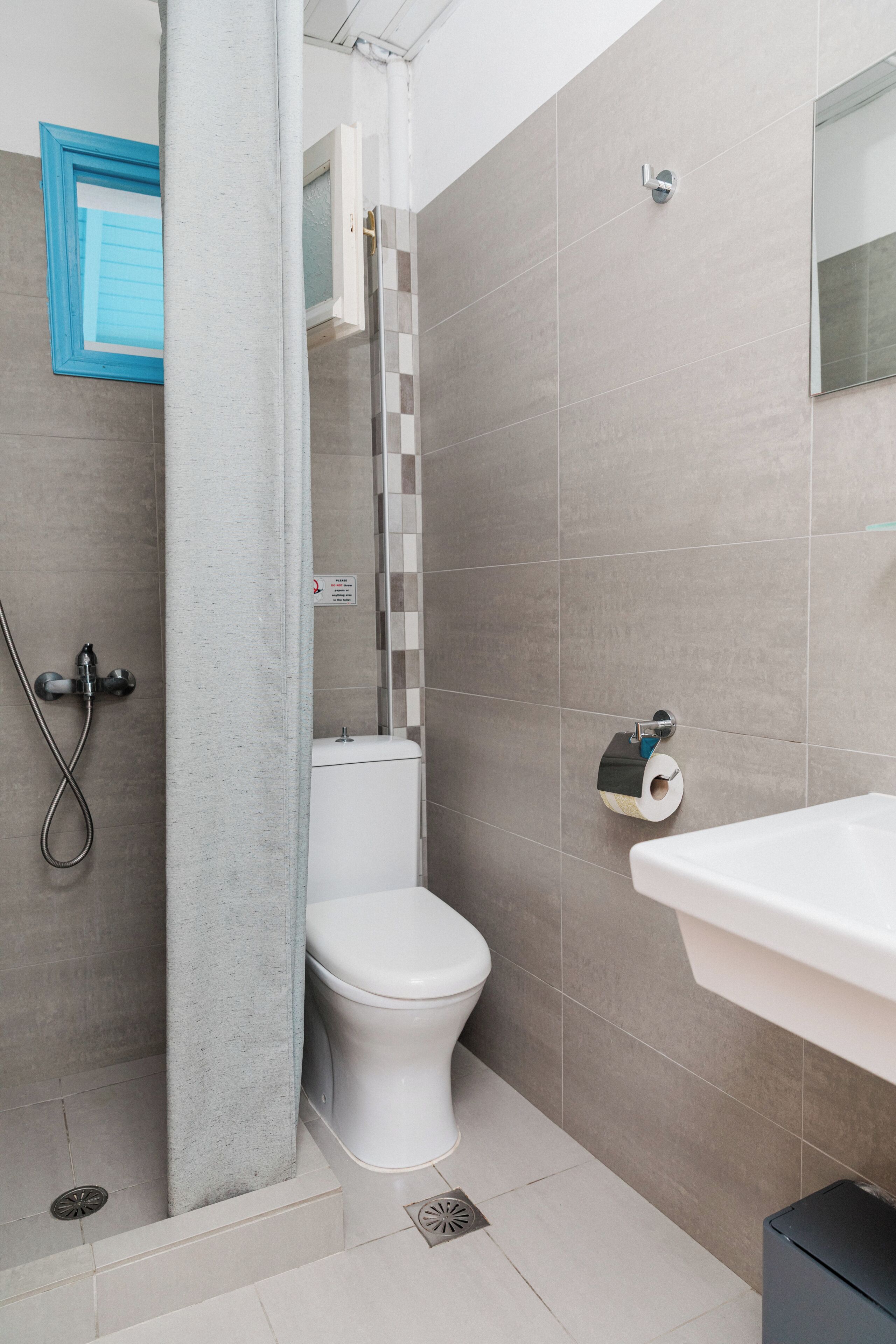 A bathroom with a toilet, shower, and sink.