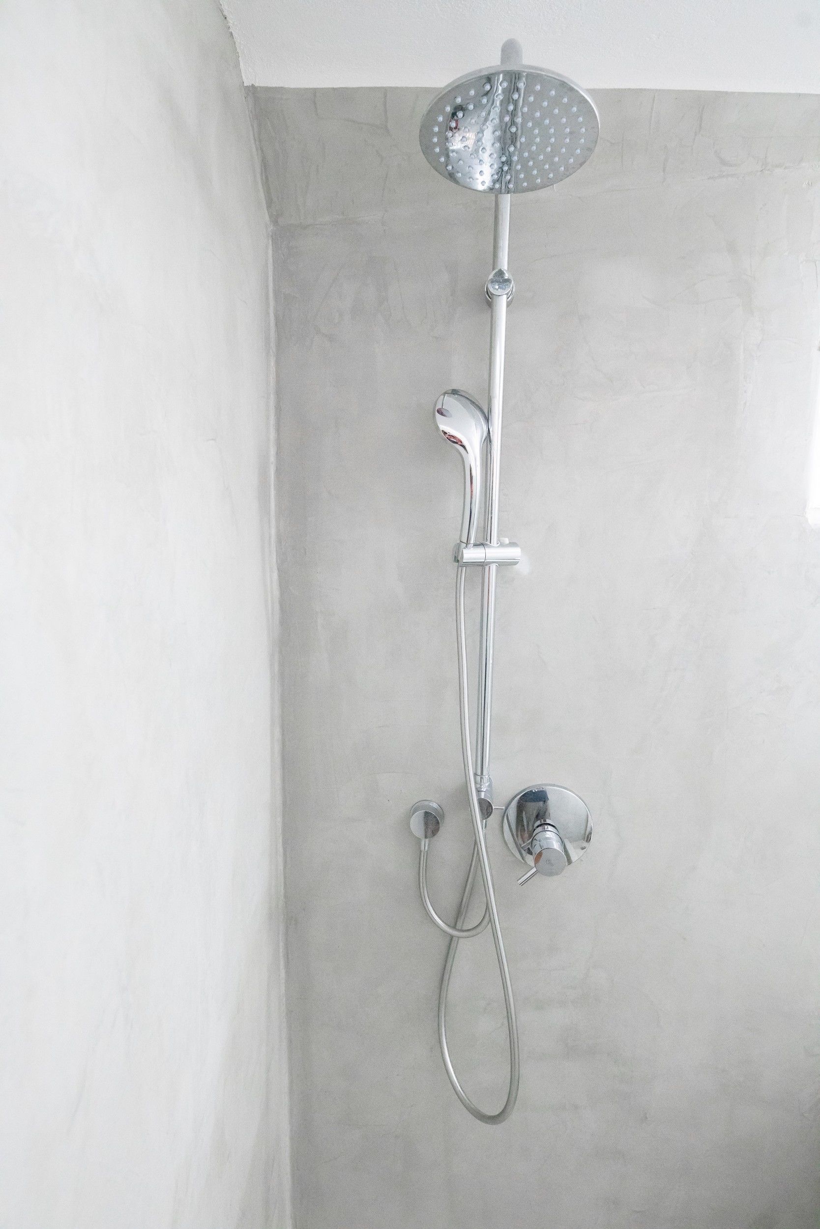 Une douche moderne dotée d’un pommeau de douche à main et d’une pomme de douche supérieure fixée au mur.