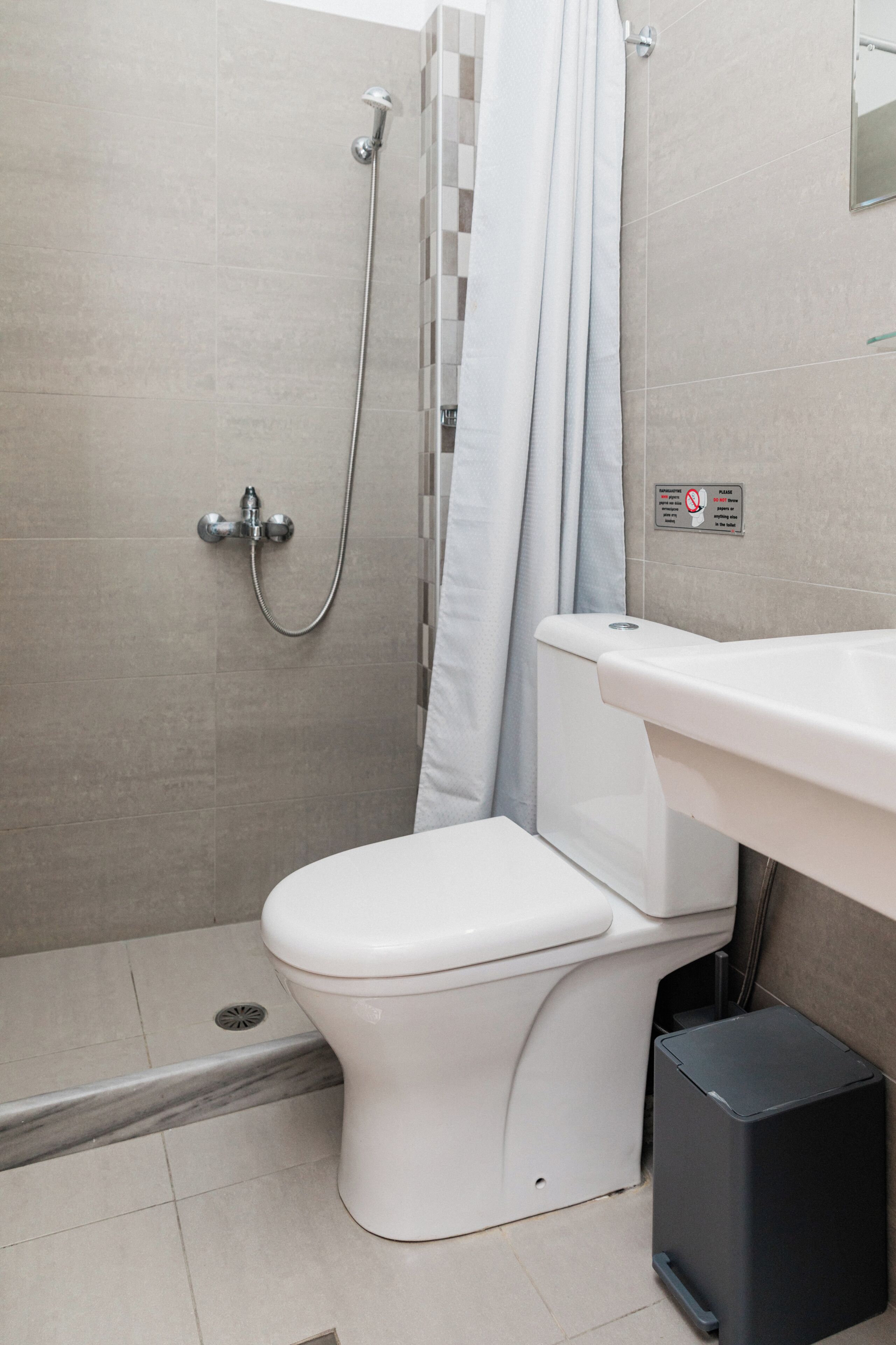 A bathroom with a toilet, a shower, and a sink.