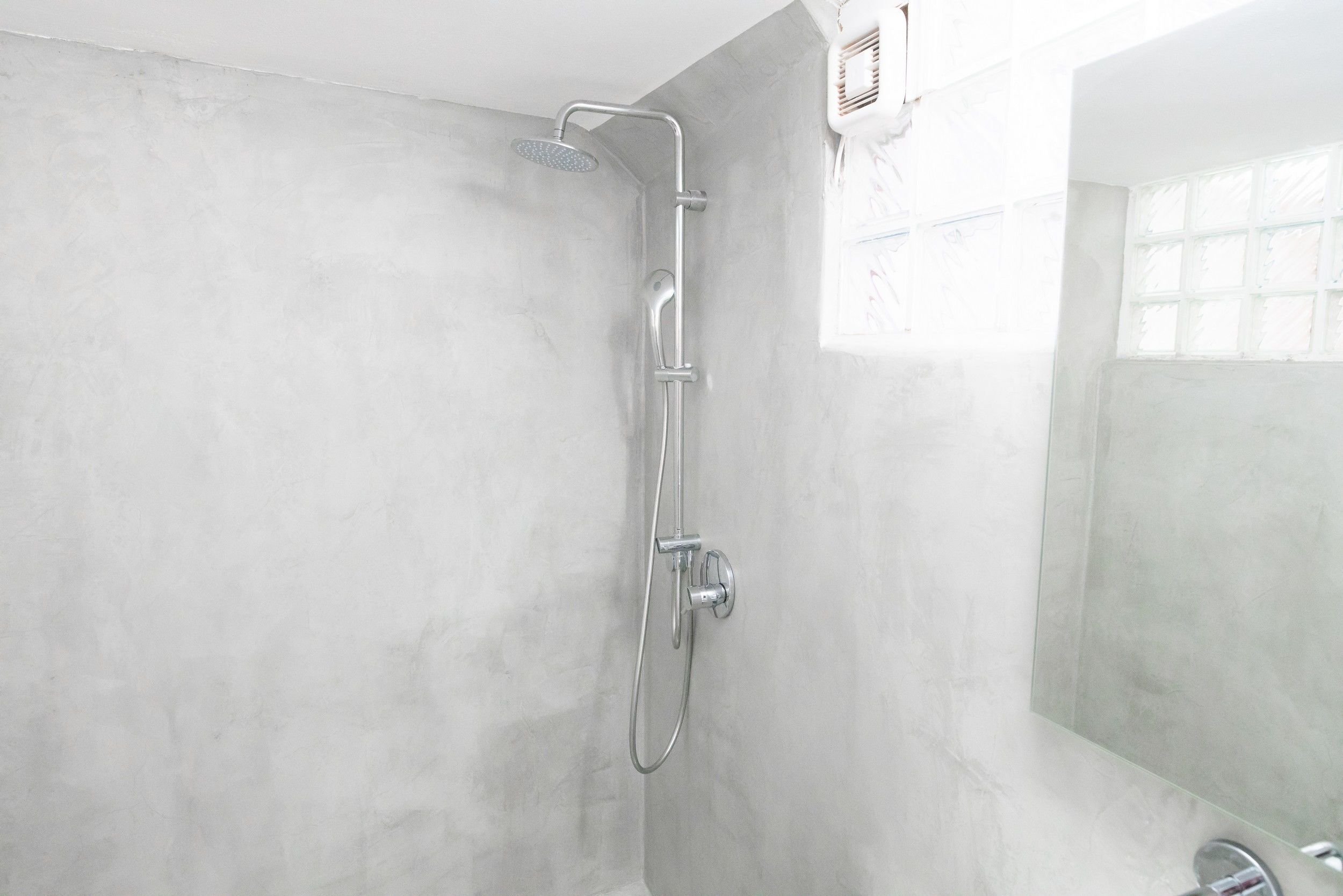 A modern shower with a handheld showerhead and a wall-mounted control panel.