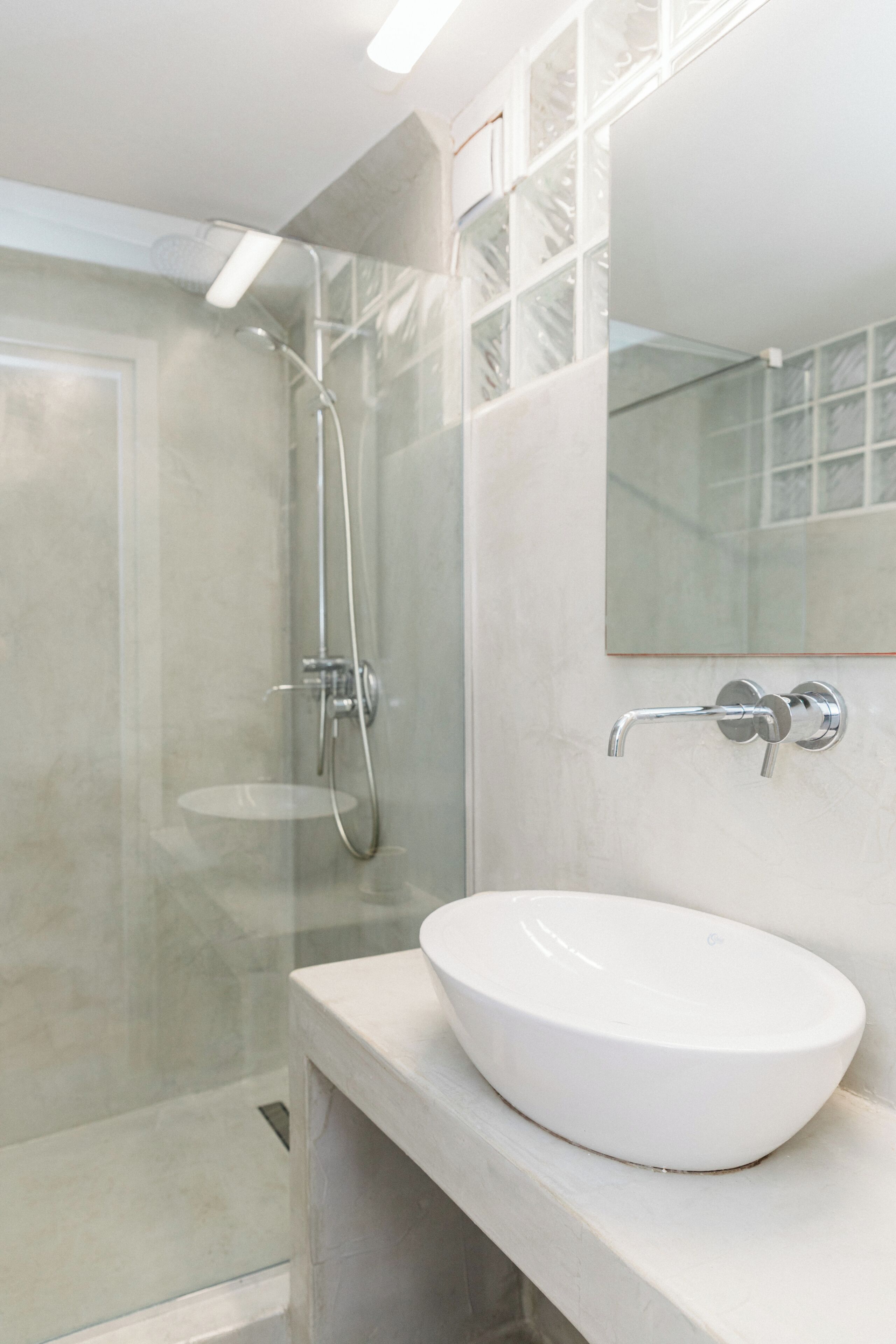 A modern bathroom with a glass shower enclosure, a white sink, and a large mirror.