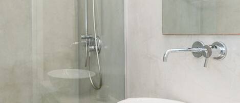 A modern bathroom with a glass shower enclosure, a white sink, and a large mirror.
