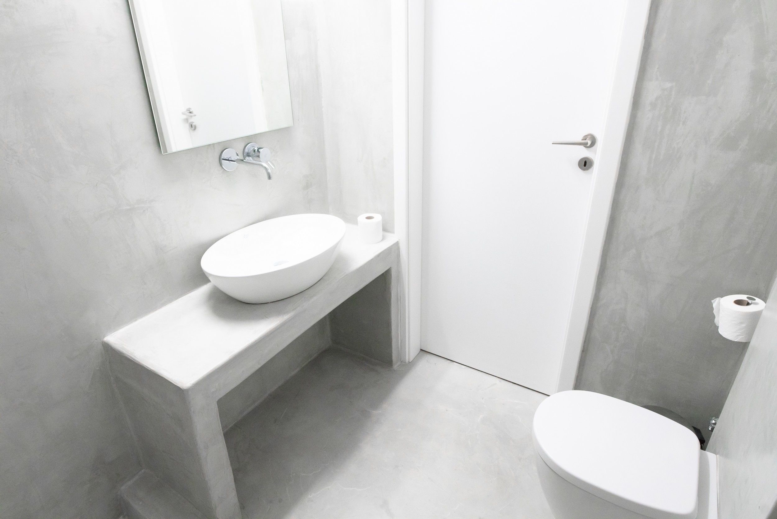 A modern bathroom with a white sink, toilet, and a door.