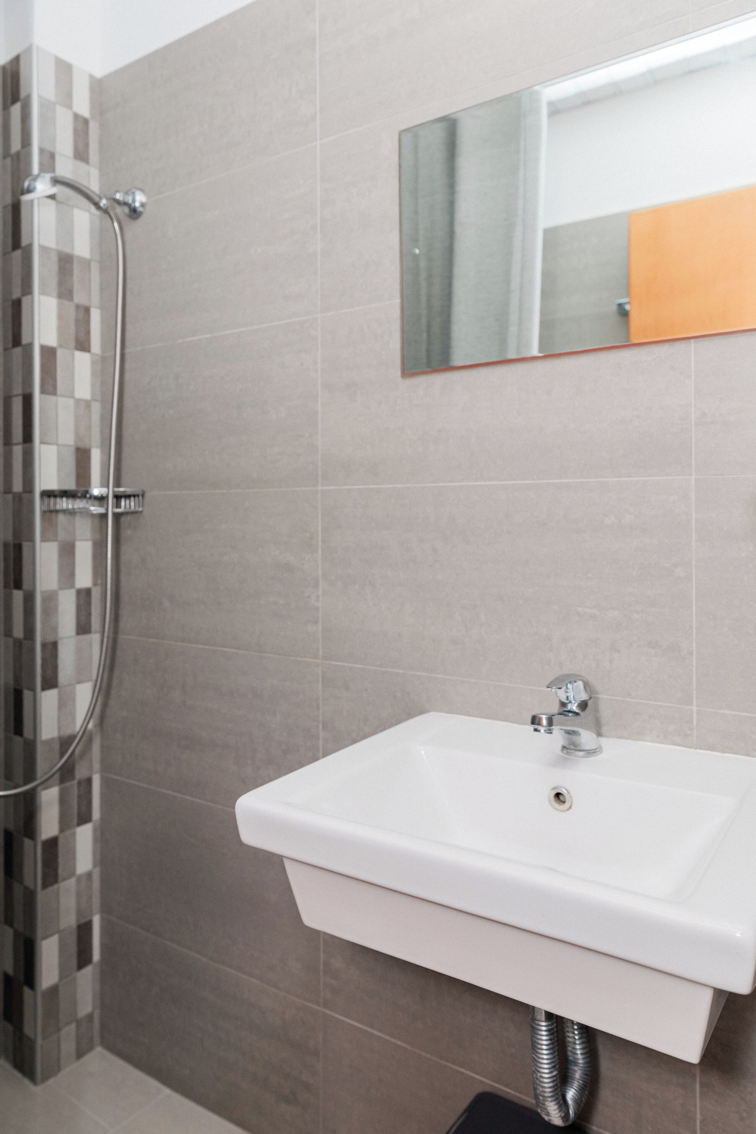 A bathroom with a shower, a sink, and a mirror.