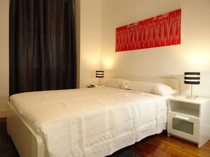 Relax in a serene space with a comfortable bed, bedside tables, and a unique art piece.