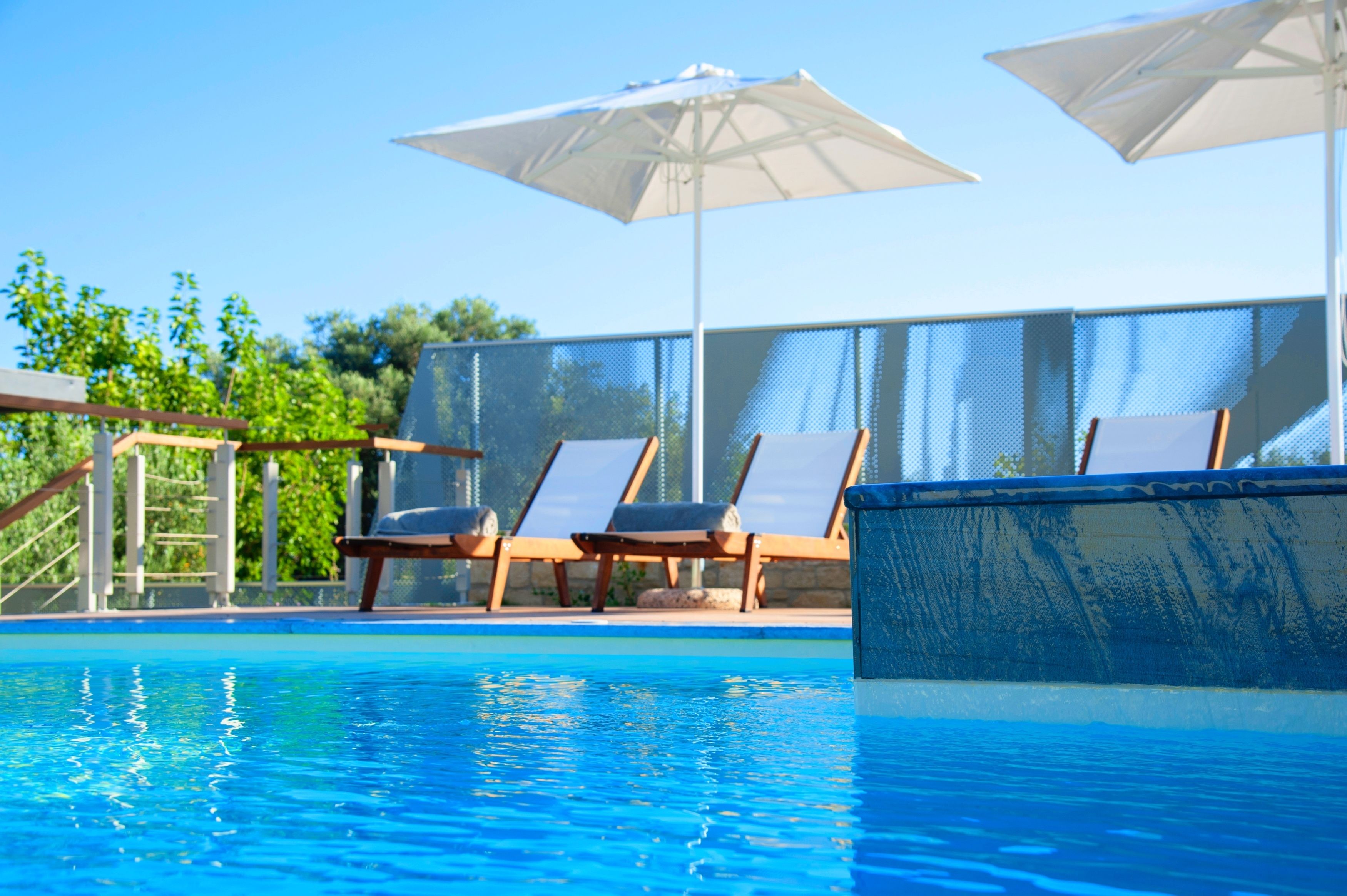 A swimming pool with lounge chairs and umbrellas.