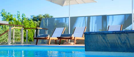A swimming pool with lounge chairs and umbrellas.