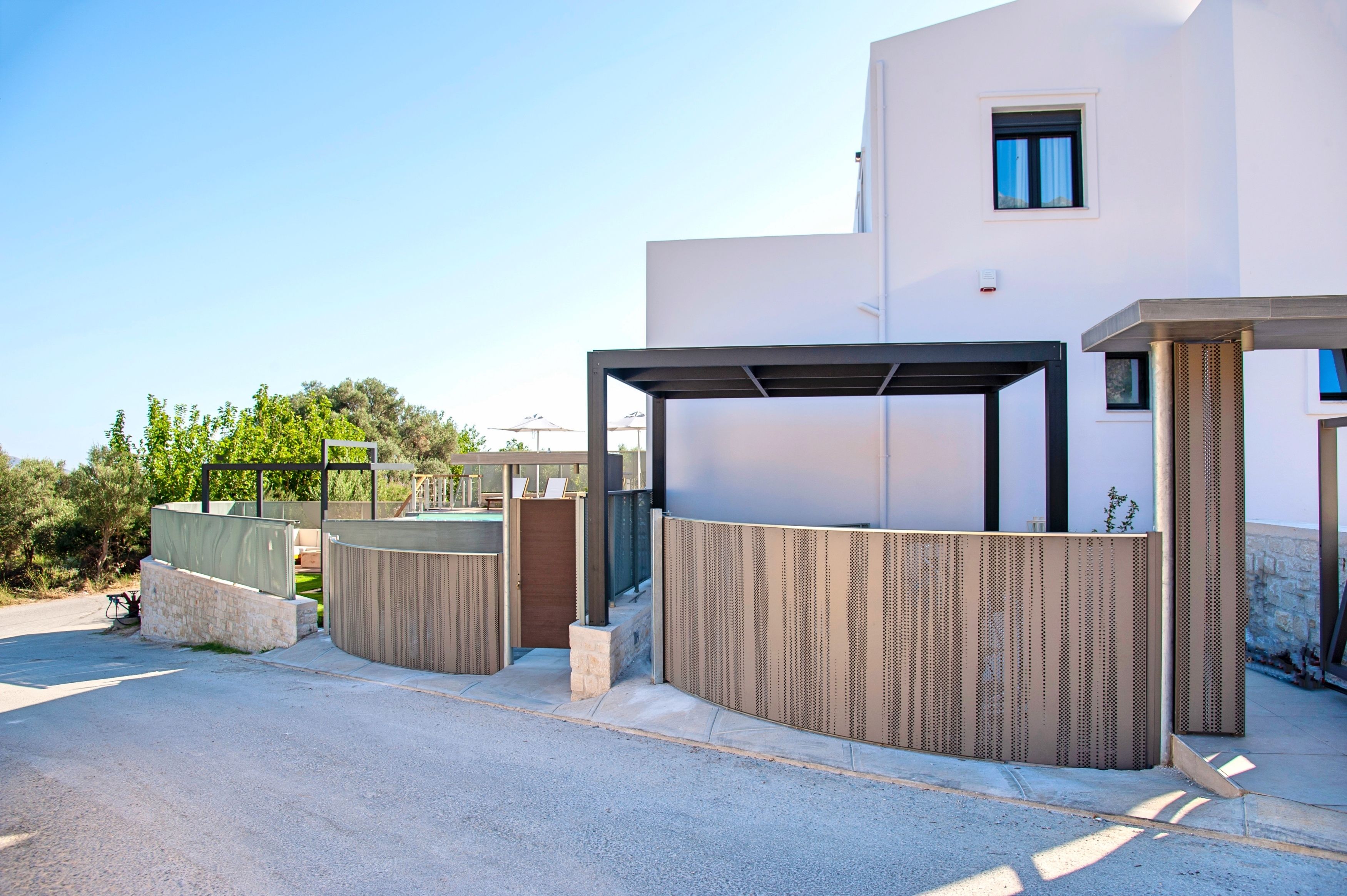 A modern building with a covered entrance, a stone wall, and a metal fence.