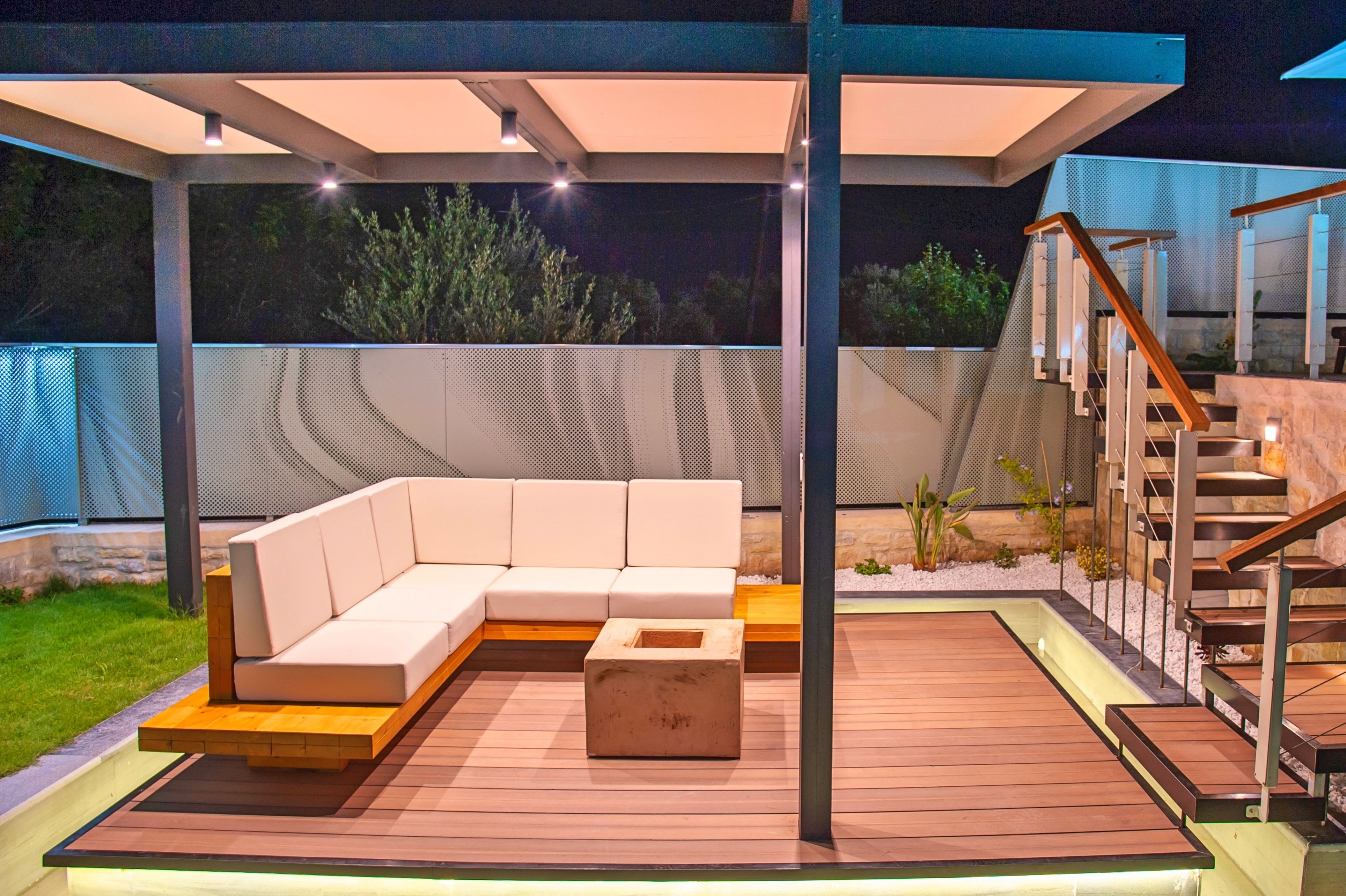 A covered outdoor seating area with a wooden deck, a built-in sofa, and a small table.