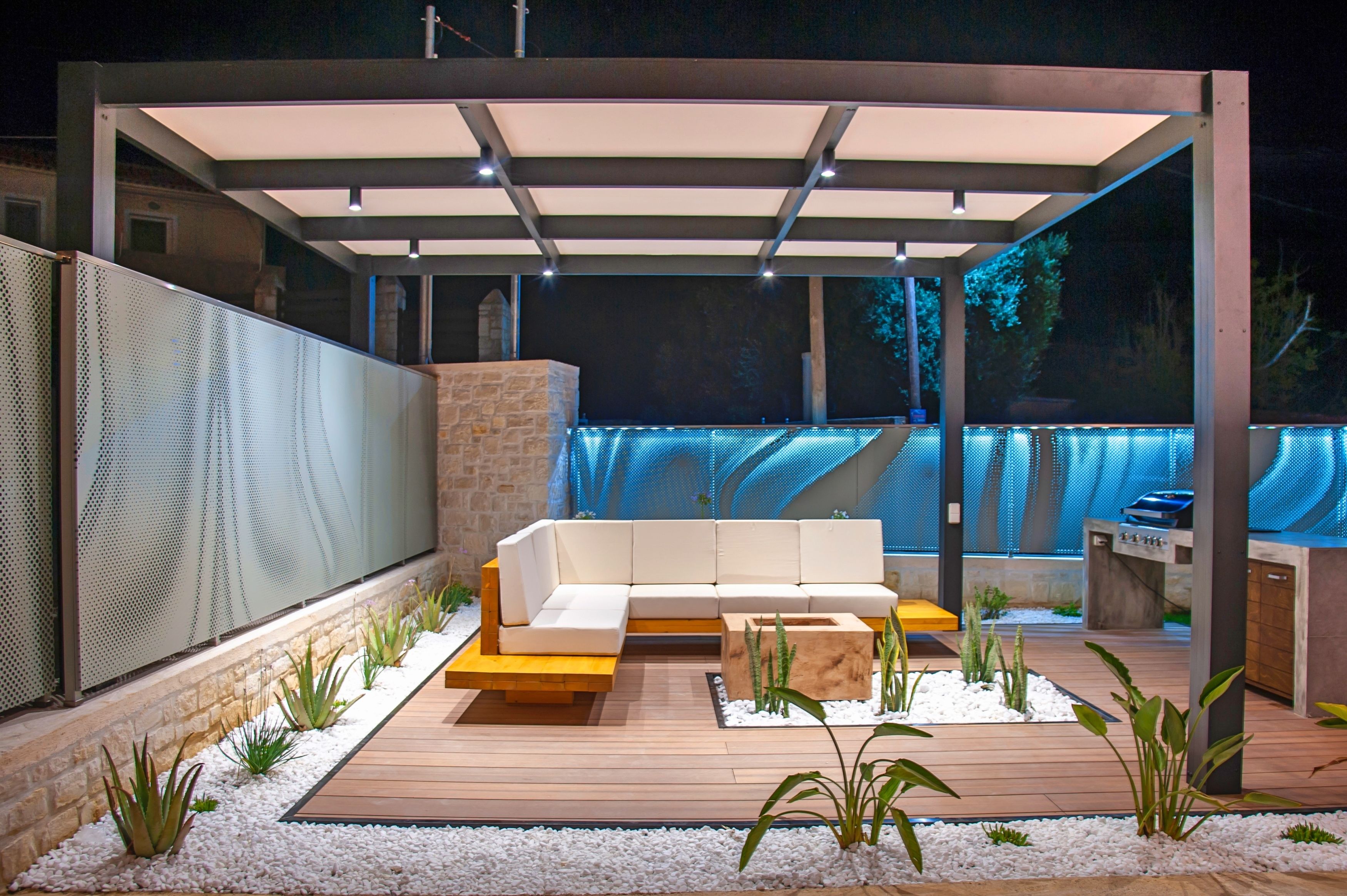 Eine Terrasse im Freien mit einer weißen Couch, einem Holzboden und einer Steinwand.