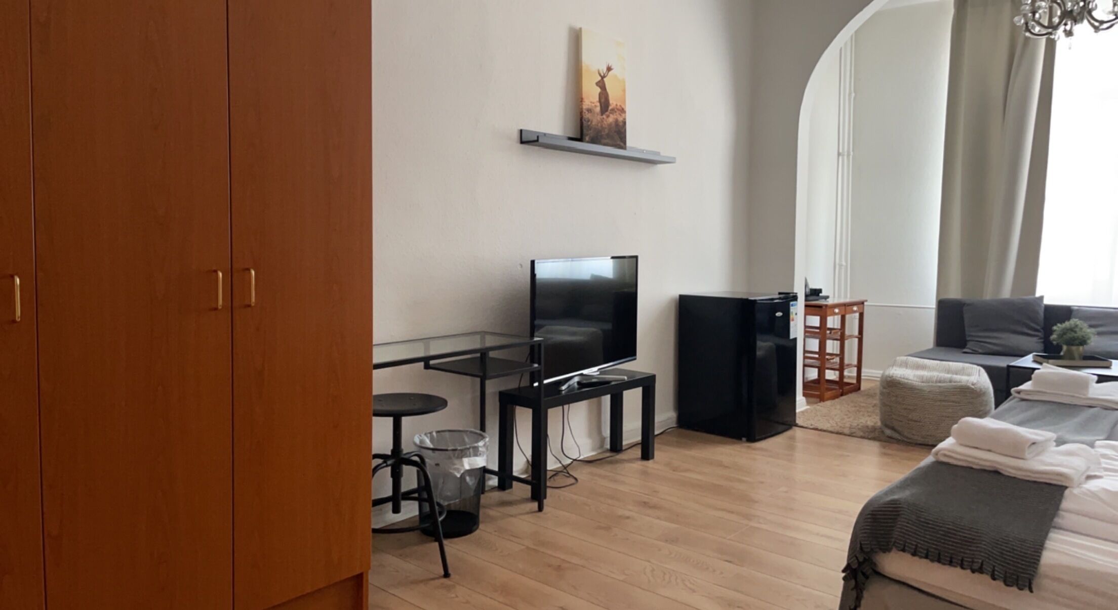 A modern living room with a TV, black furniture, a wooden cabinet, and a small table with a chair.