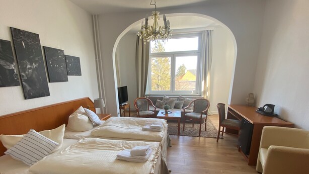 Quarto de hotel com uma cama grande, uma escrivaninha, uma cadeira e uma televisão.