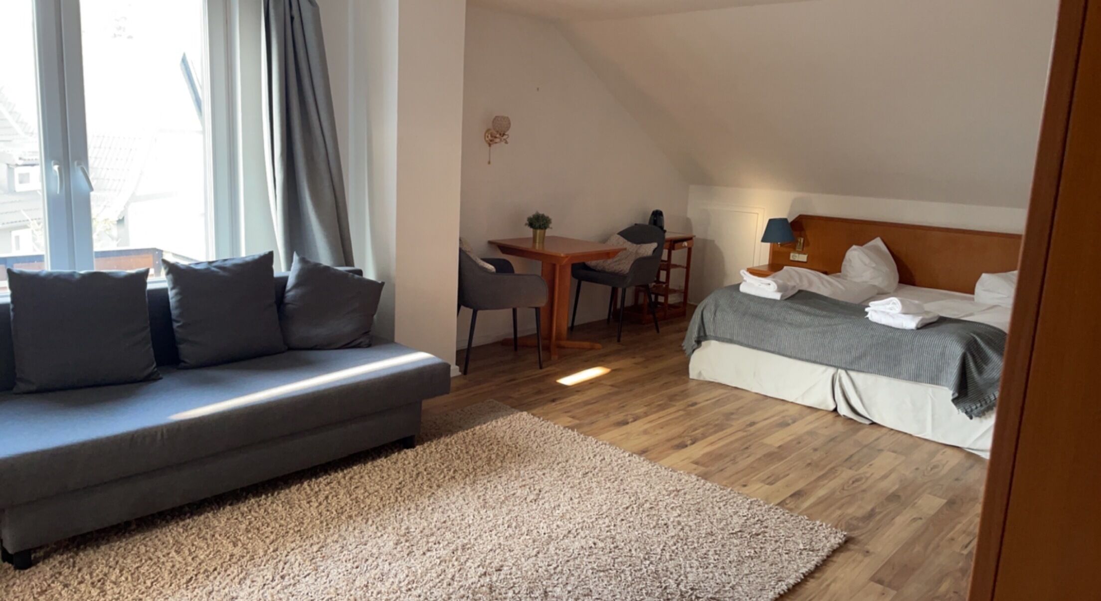 Et moderne hotelværelse med sofa, spisebord, seng og skrivebord.