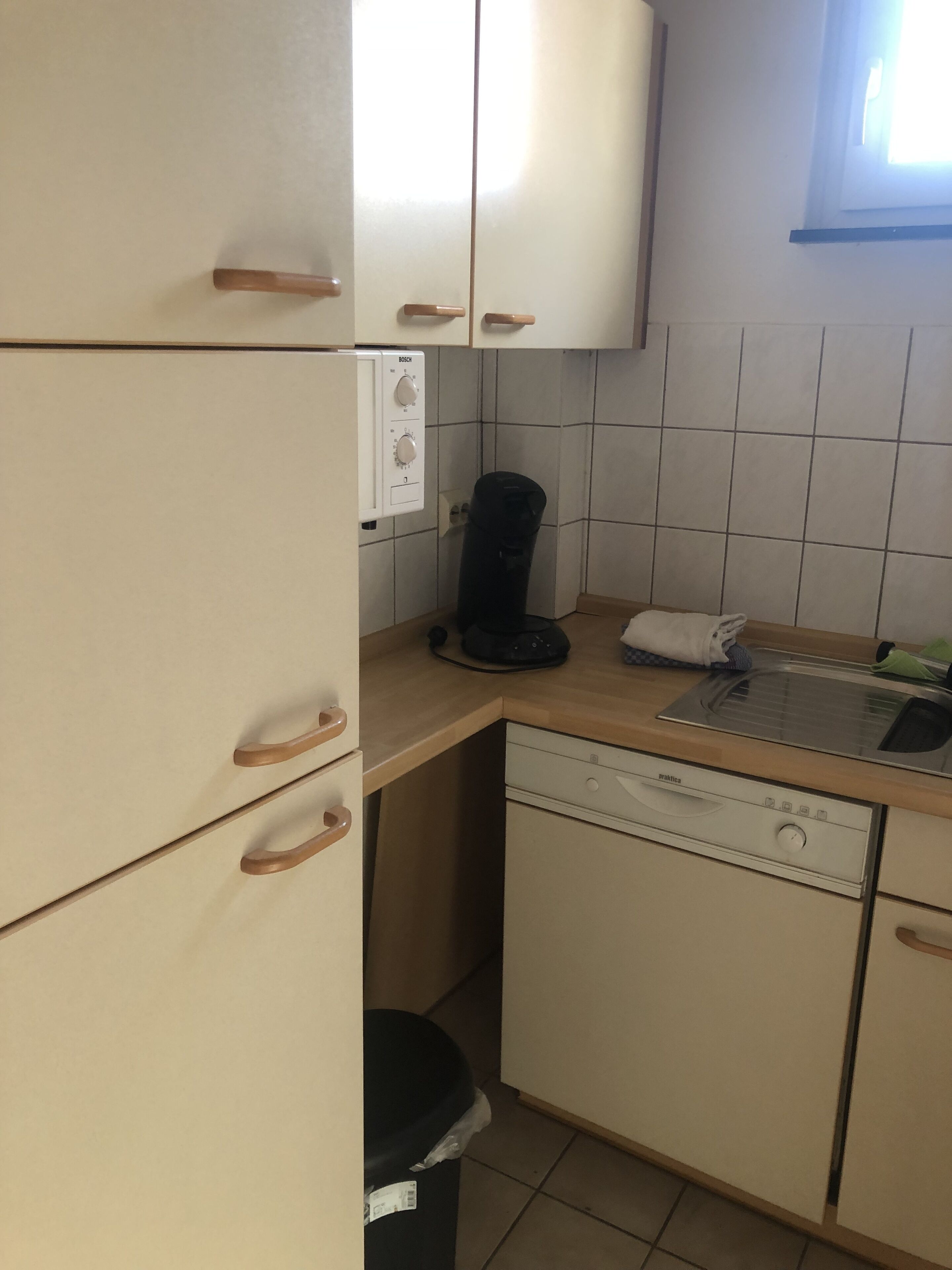 A compact kitchen with a Bosch coffee maker, a dishwasher, and a sink.