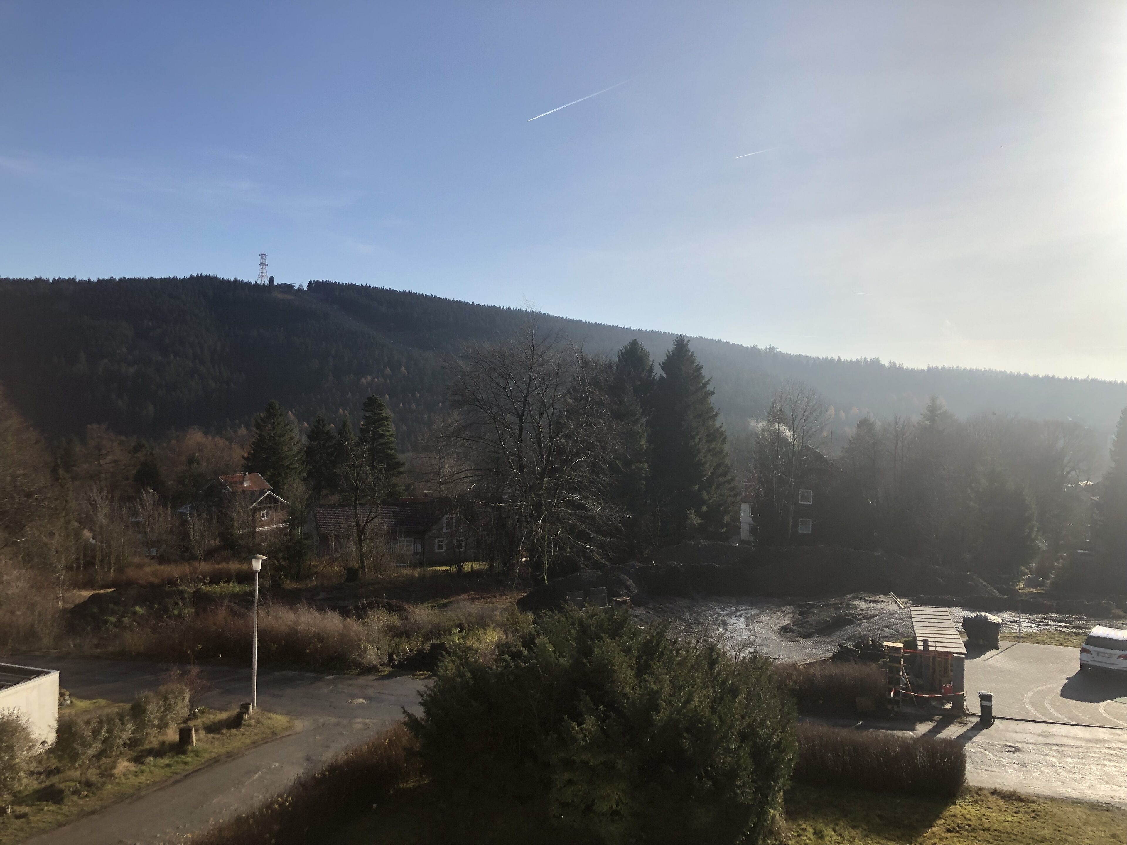 Un paysage rural avec une route, un petit bâtiment et une colline boisée.