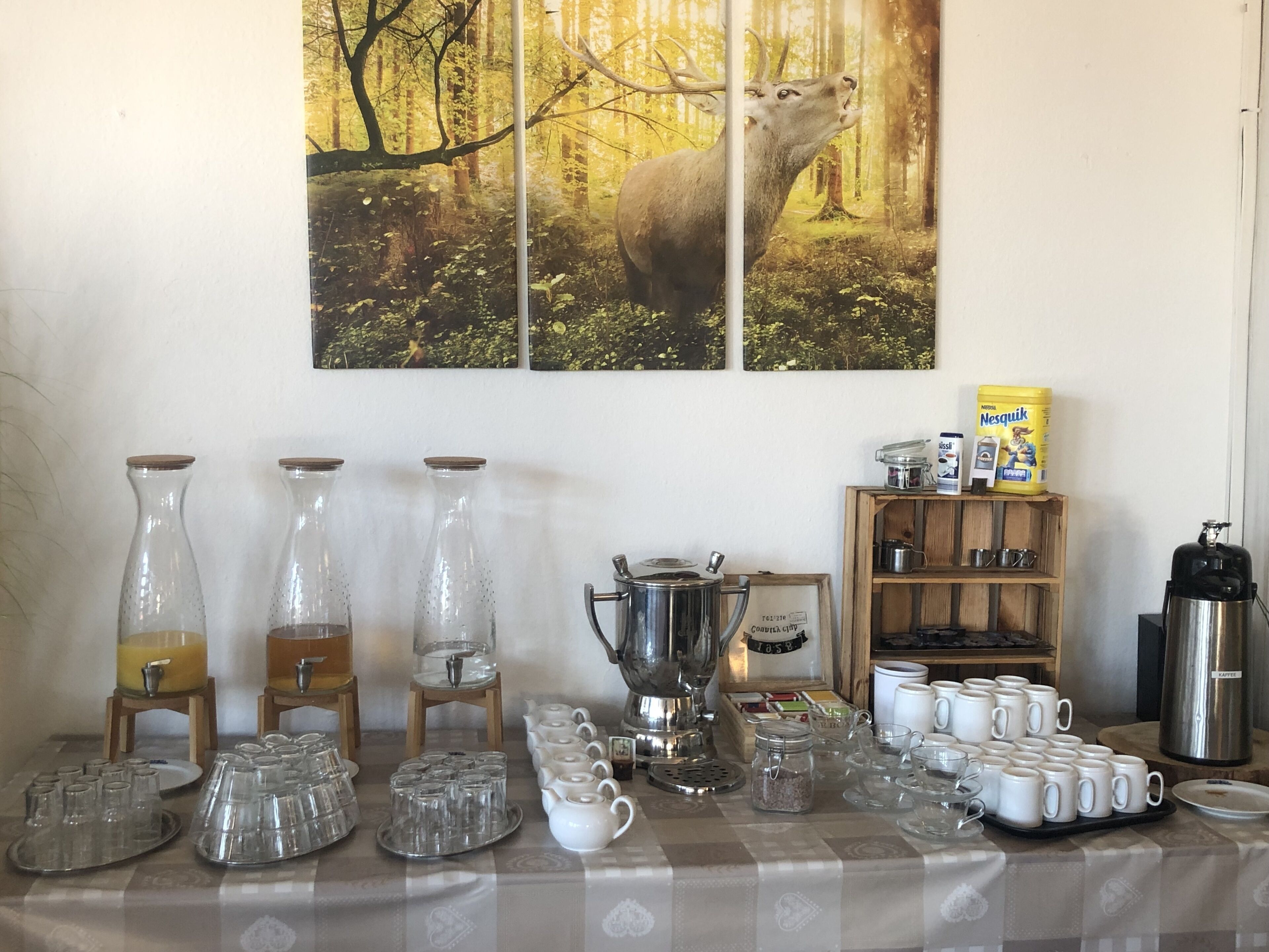 Ein Frühstückstisch mit verschiedenen Gläsern, einer Kaffeekanne und einer Schachtel Nesquik.