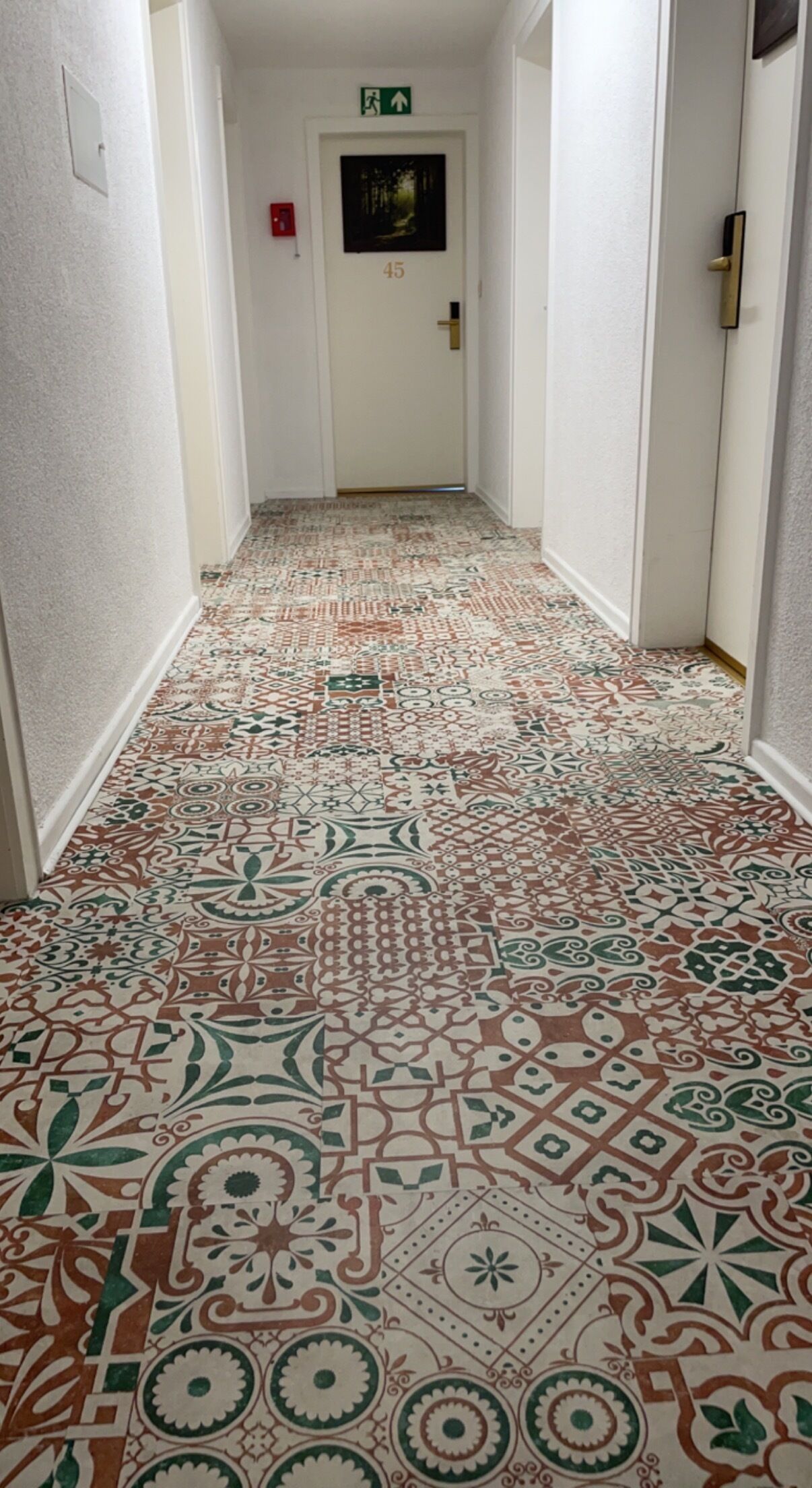 A hallway with patterned carpet and a door with a number.