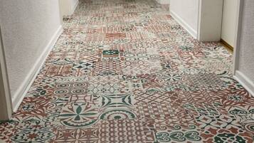 A hallway with patterned carpet and a door with a number.