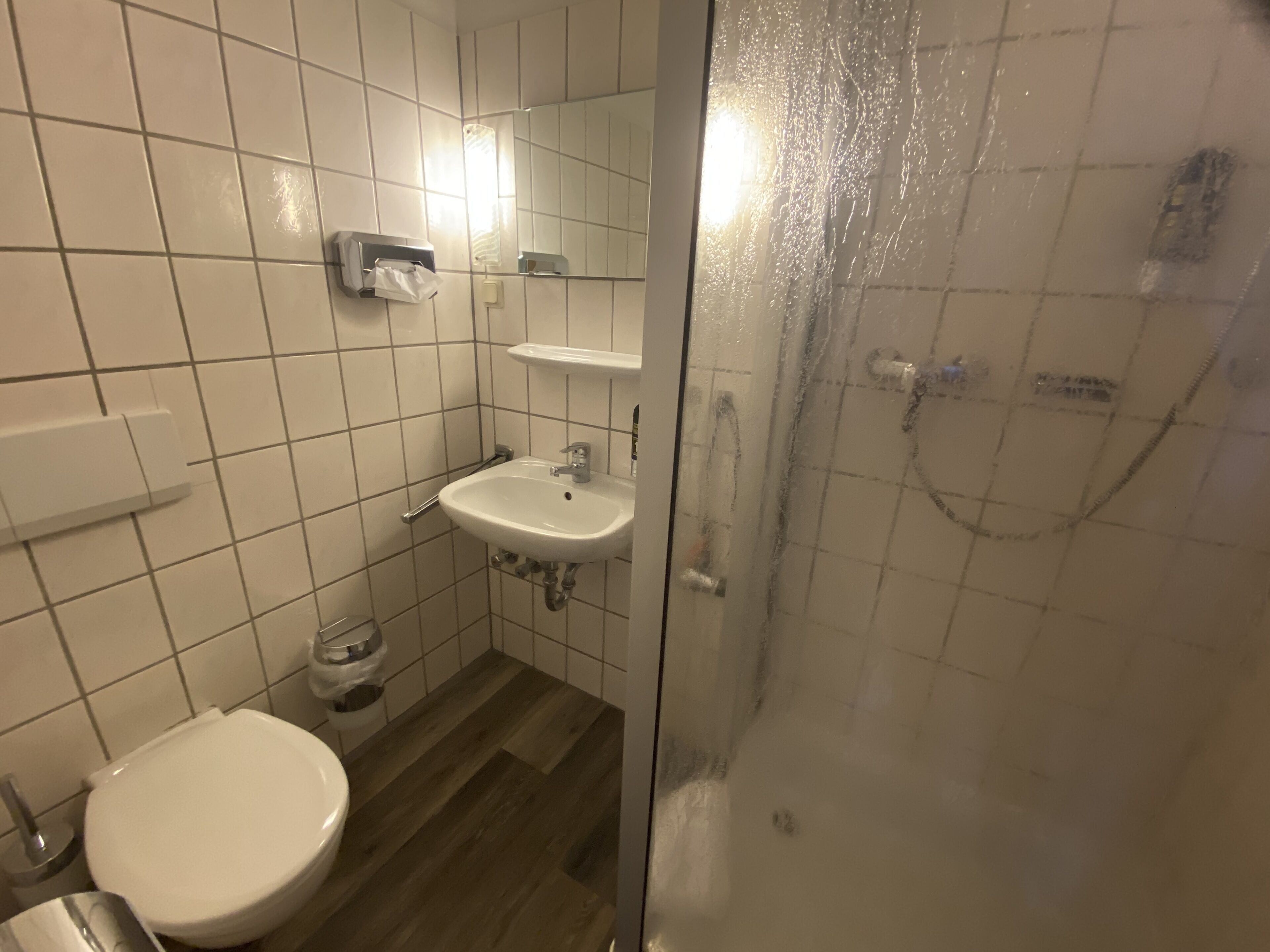 Et badeværelse med toilet, vask og brusebad.