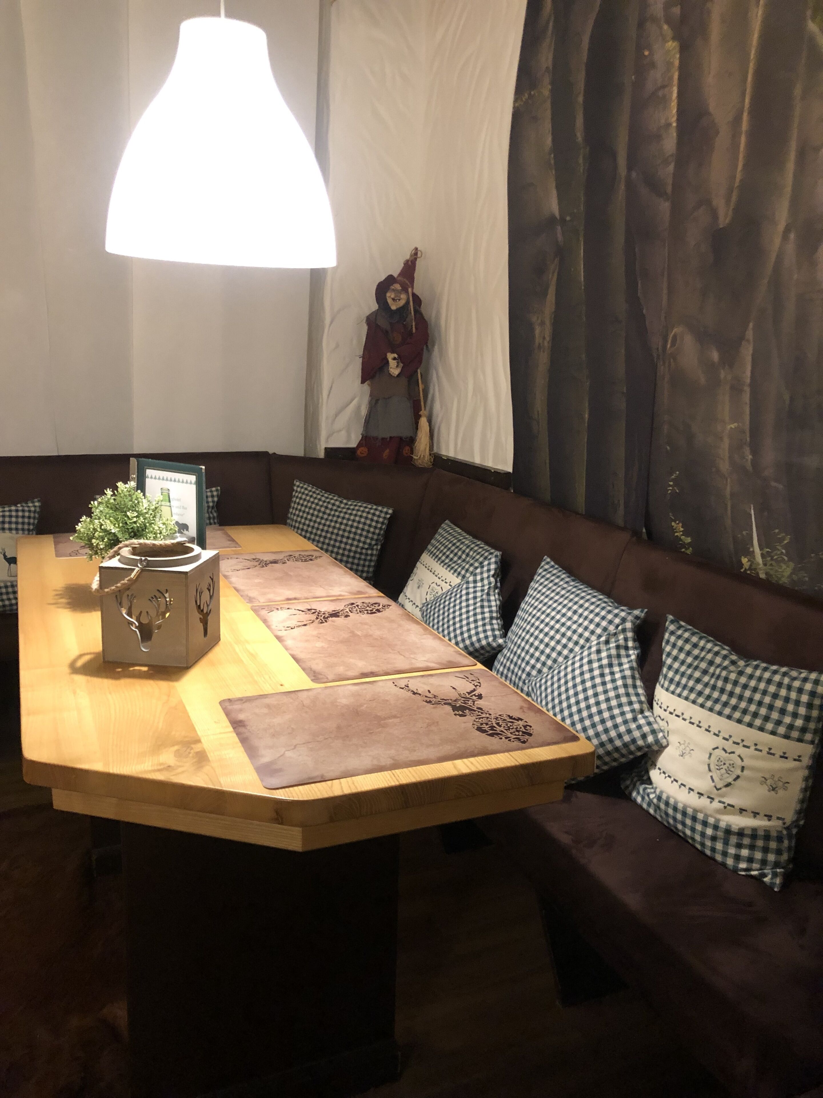 A cozy dining area with a wooden table, checkered cushions, and a decorative figure.