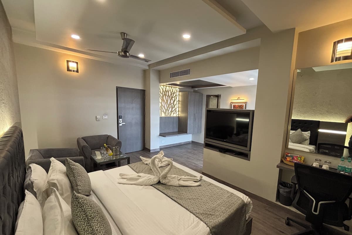 A hotel room with a bed, a desk, a chair, a TV, and a ceiling fan.