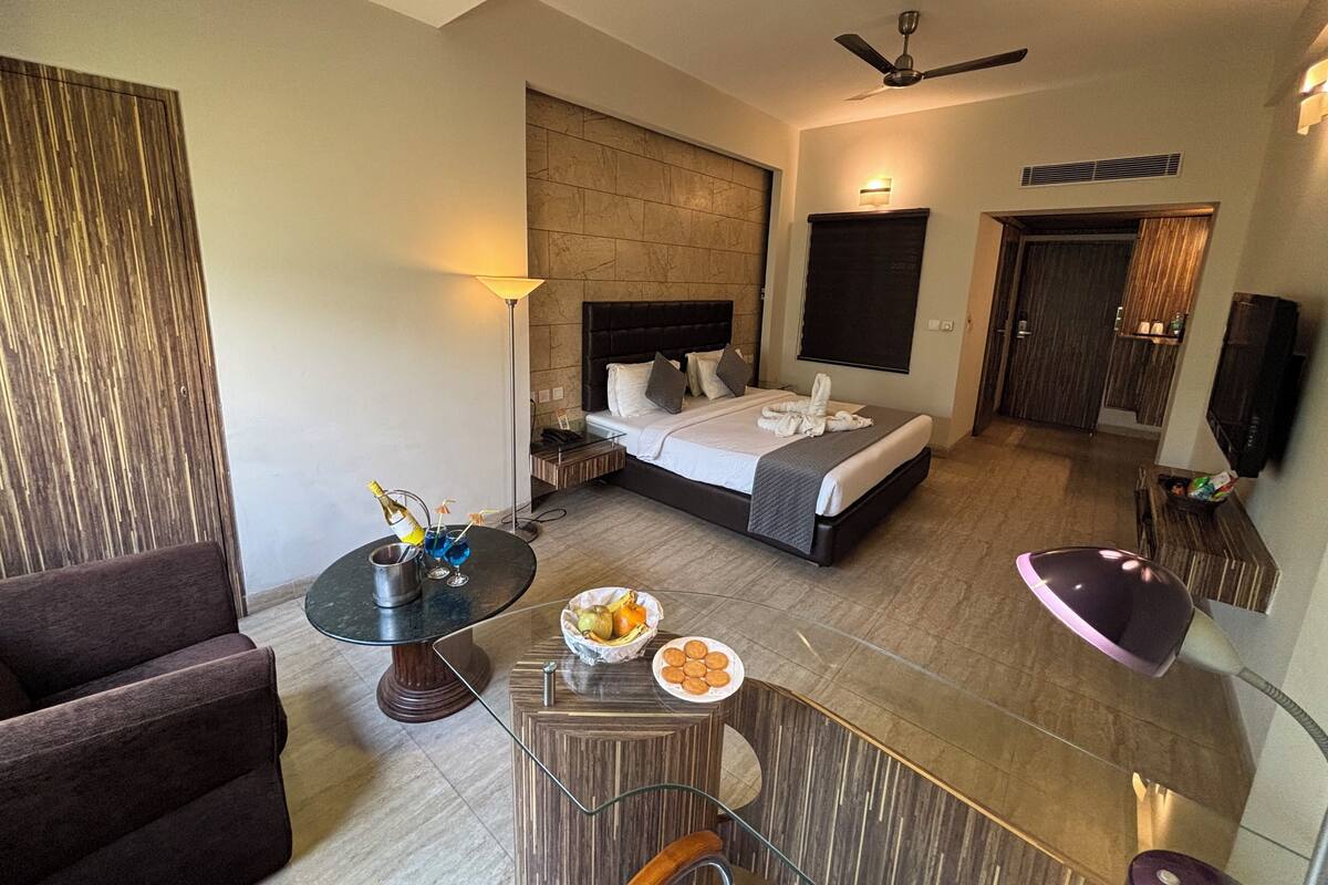 A hotel room with a bed, a desk, a chair, a TV, and a ceiling fan.
