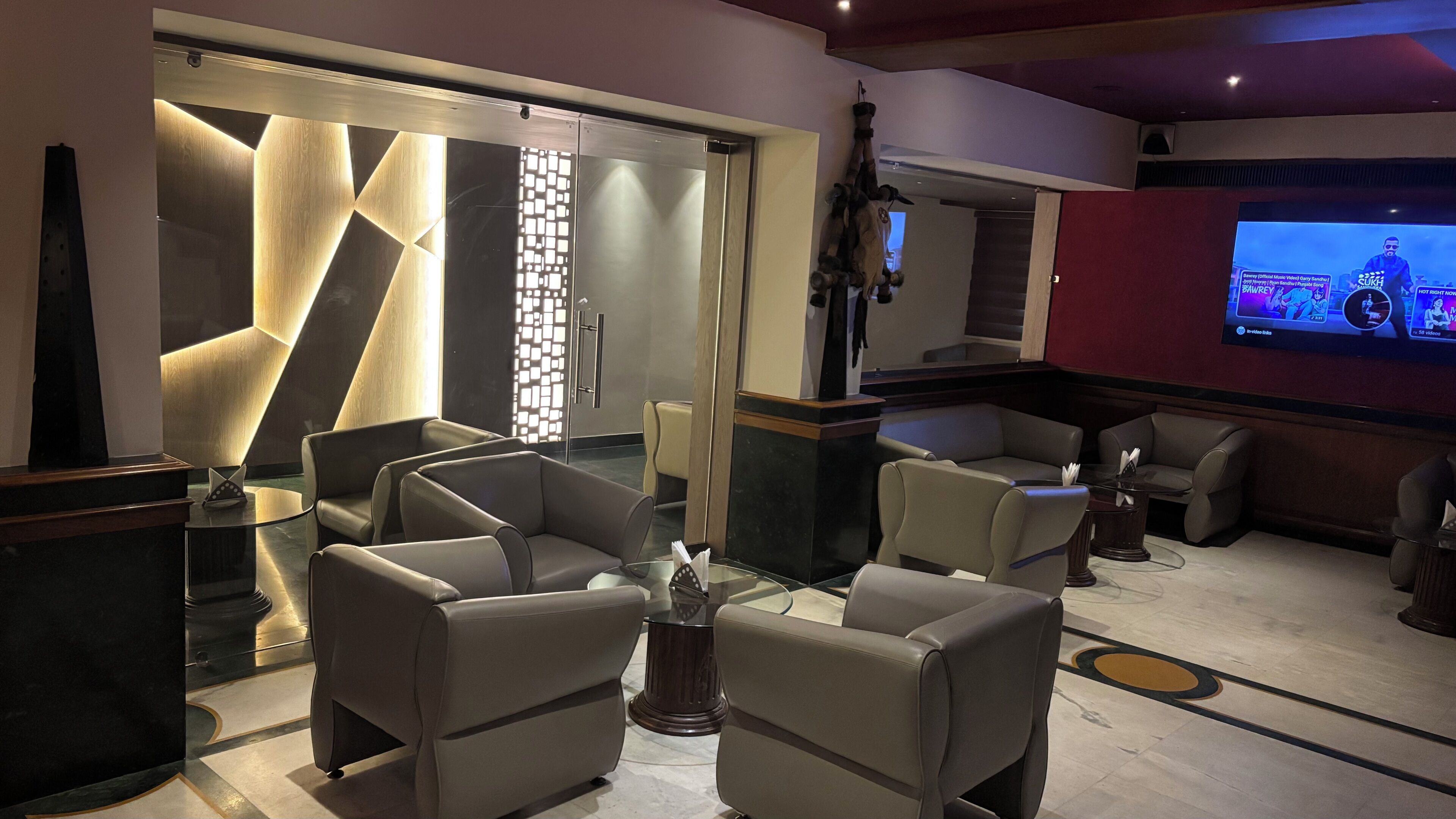 A modern interior with seating, a TV screen, and a decorative wall.