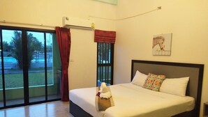 A hotel room with a large bed, a window with red curtains, an air conditioning unit, and a painting on the wall. - RoomQuest Chonburi Phanat Nikhom (Phanat Nikhom)