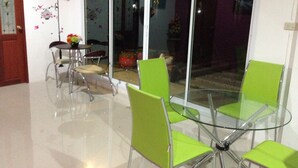 A dining area with a glass table and four green chairs. - RoomQuest Chonburi Phanat Nikhom (Phanat Nikhom)