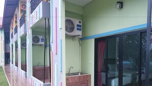 A hotel with a covered outdoor area, air conditioning units, a sink, and a sliding glass door.
