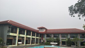 A hotel with a swimming pool, multiple balconies, and a red roof.