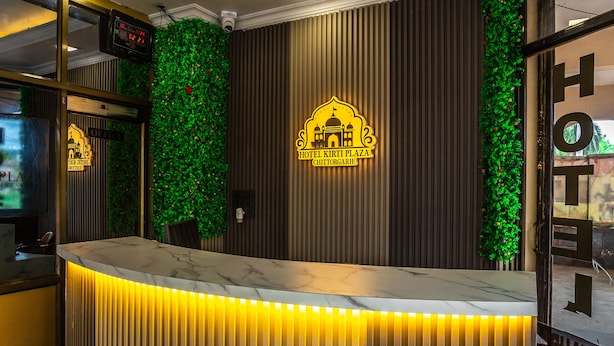 Un mostrador de recepción de hotel con diseño moderno, que incluye un jardín vertical y un logotipo en la pared.
