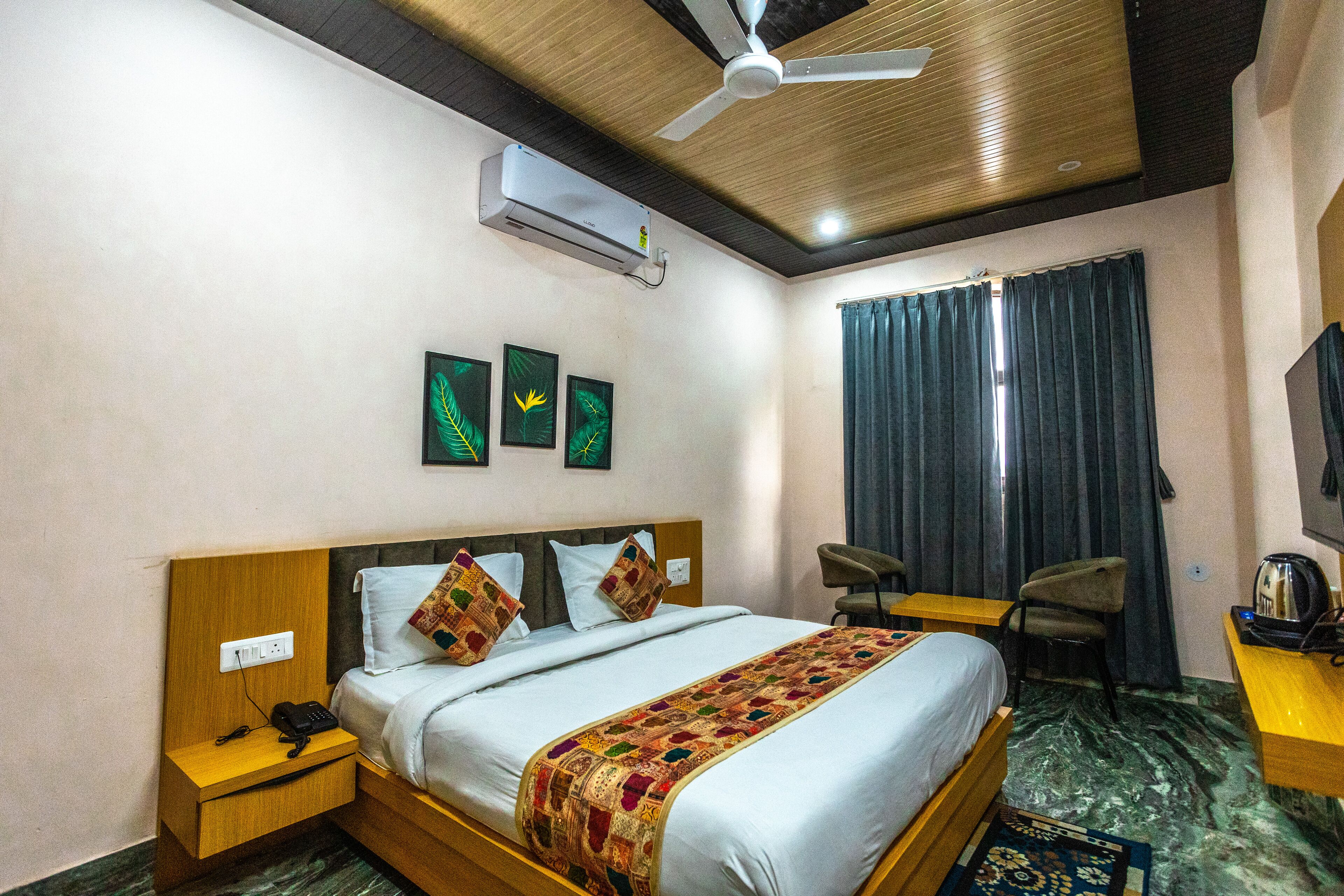 Quarto de hotel com cama, mesa de cabeceira, cadeira, escrivaninha e ar condicionado.