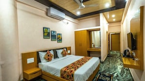 Un dormitorio con cama, mesitas de noche, armario de madera, ventilador de techo, aire acondicionado y televisor.