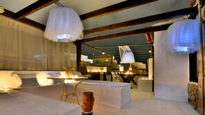 Ein gemütliches, helles Interieur mit Sitzgelegenheiten, Tischen und Pendelleuchten.