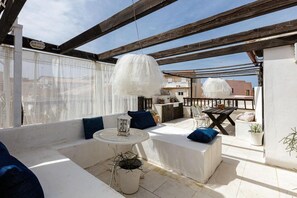 A rooftop patio with a white sofa set, a round table, and a hanging light fixture. - Antonia's House (Rethymno)