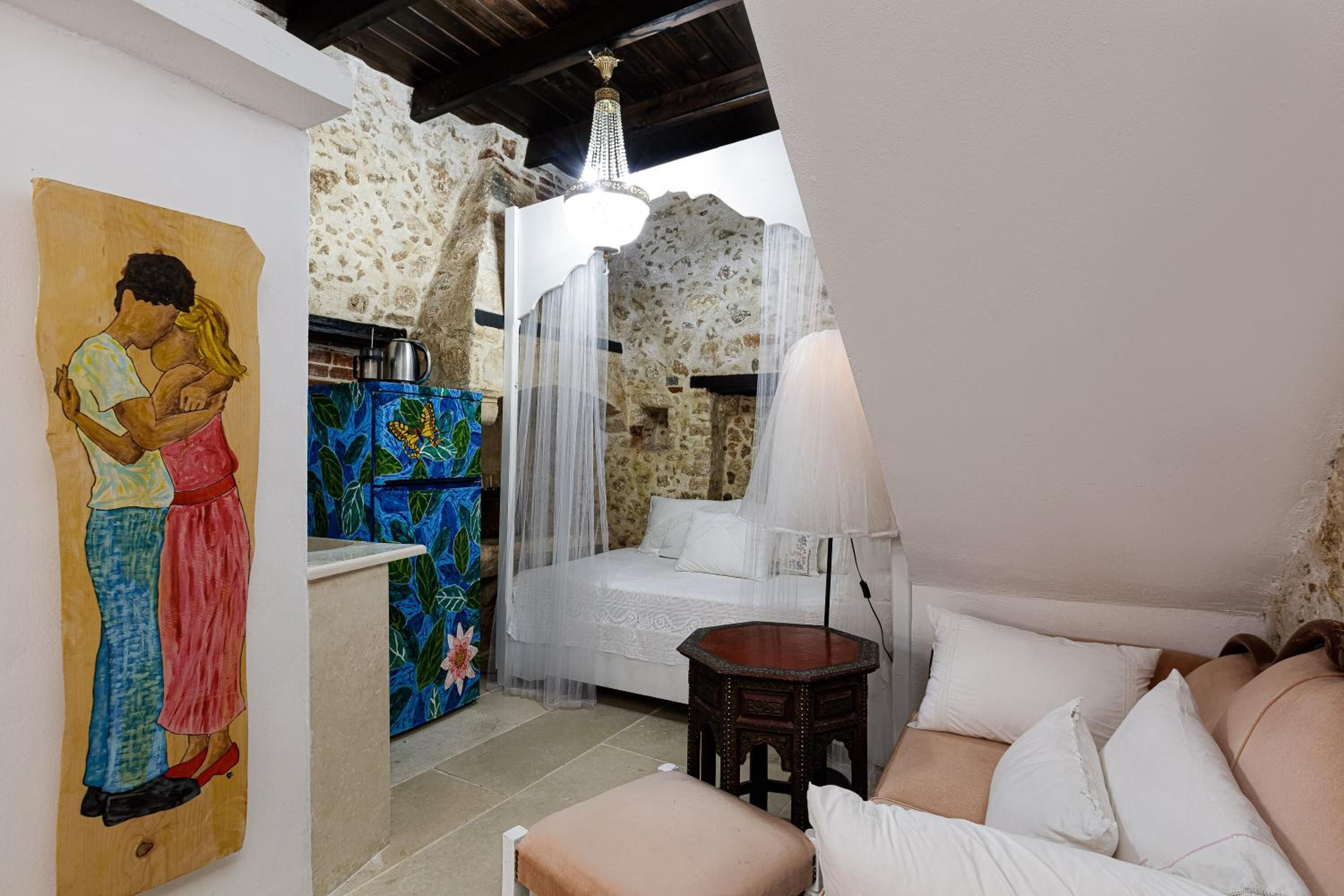 A bedroom with a bed, bedside table, and a painting on the wall.