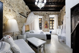 Una habitación acogedora con pared de piedra, cama con dosel, mesita de noche, lámpara y un cuadro en la pared.