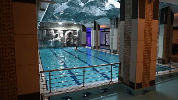 An indoor swimming pool with a rocky wall backdrop and a modern design. - Barden Hotel (Siirt)