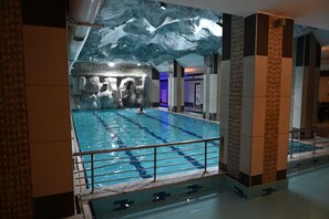Piscina interior con pared de roca de fondo y diseño moderno.