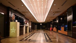 A hotel lobby with a modern design, featuring a reception desk, a large chandelier, and a carpeted floor. - Barden Hotel (Siirt)