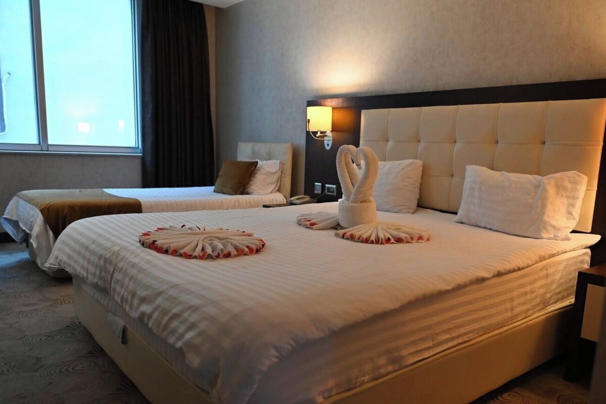 Ein Hotelzimmer mit zwei Betten, einem großen Fenster und einer Wandleuchte.