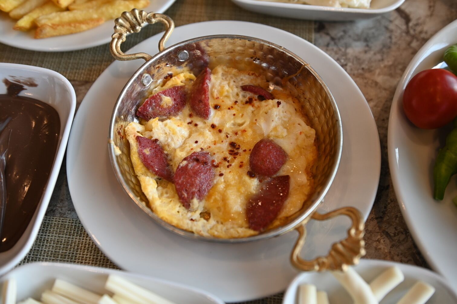 A dish with a golden-brown crust, possibly a baked casserole, served in a decorative metal bowl with handles.