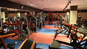 A gym with various exercise machines, mirrors, and a red and blue floor. - Barden Hotel (Siirt)