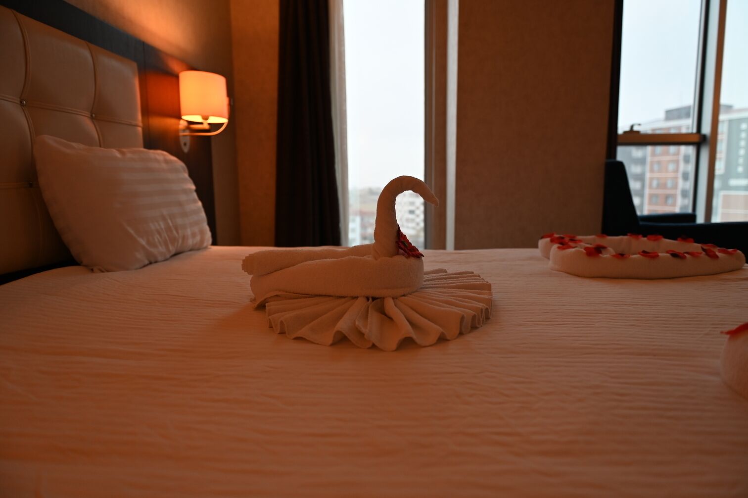 Une chambre d’hôtel avec un lit parfaitement fait, une serviette en forme de cygne et un cygne décoratif posé sur le lit.