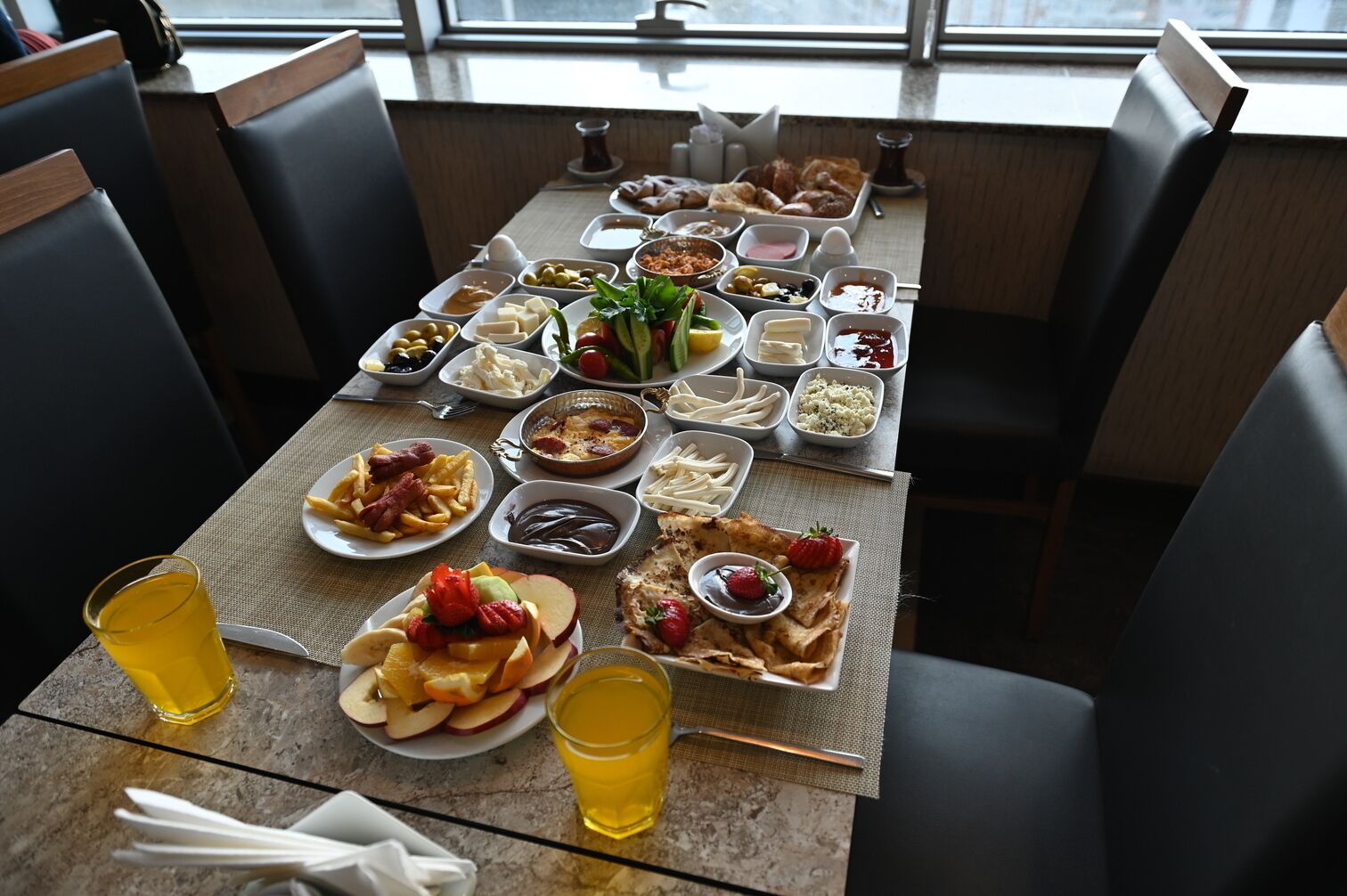 Ein reichhaltiges Frühstücksbuffet mit verschiedenen Speisen, darunter Obst, Backwaren und eine Auswahl an Käse.